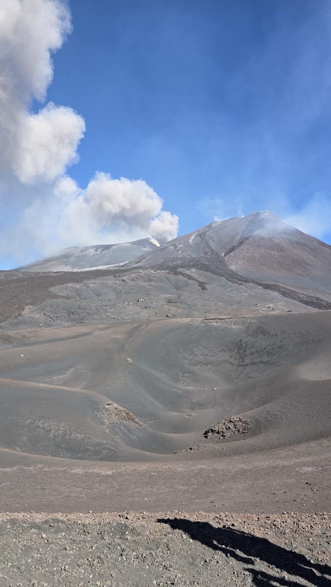 Dark volcanic ground beneath a blue sky.