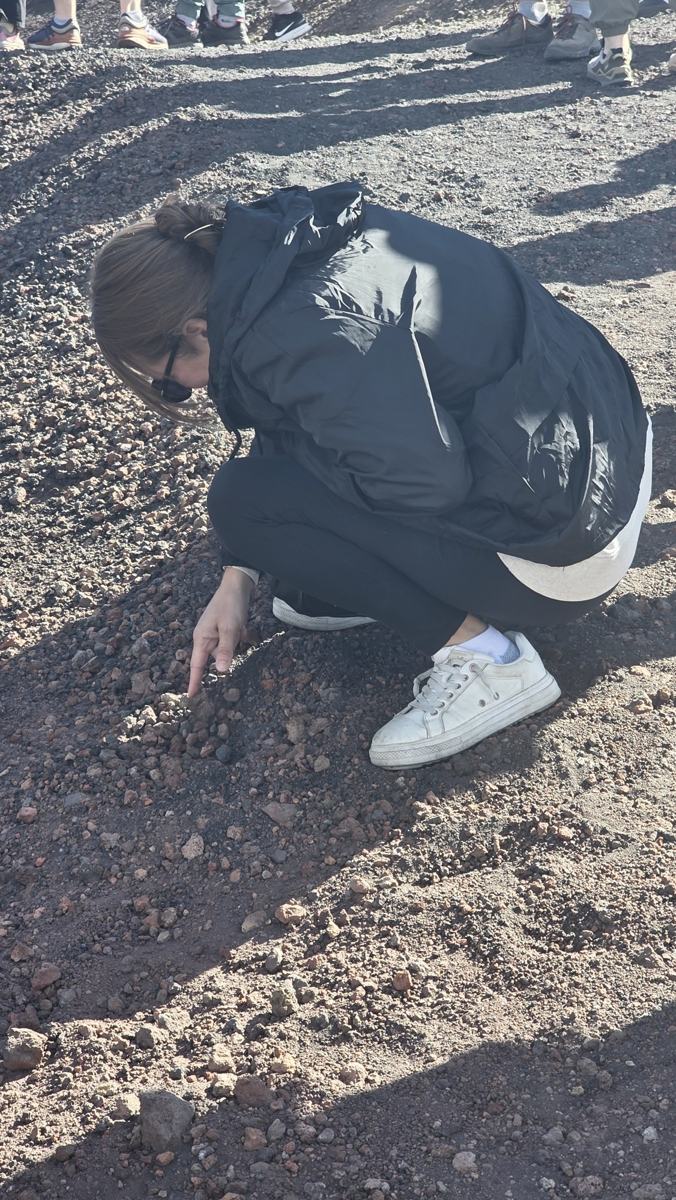 Jenn looking closely at the volcanic ground.